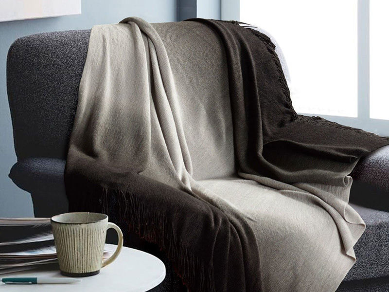 Image of grey chair with a black and white ombre blanket draped across